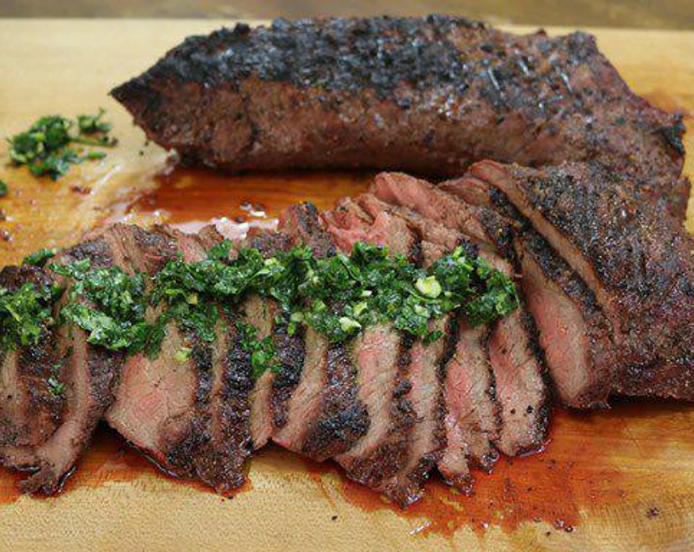 A cooked tri-tip roast on a cutting board with visible grain lines running in two different directions from the center toward the tip and wider end