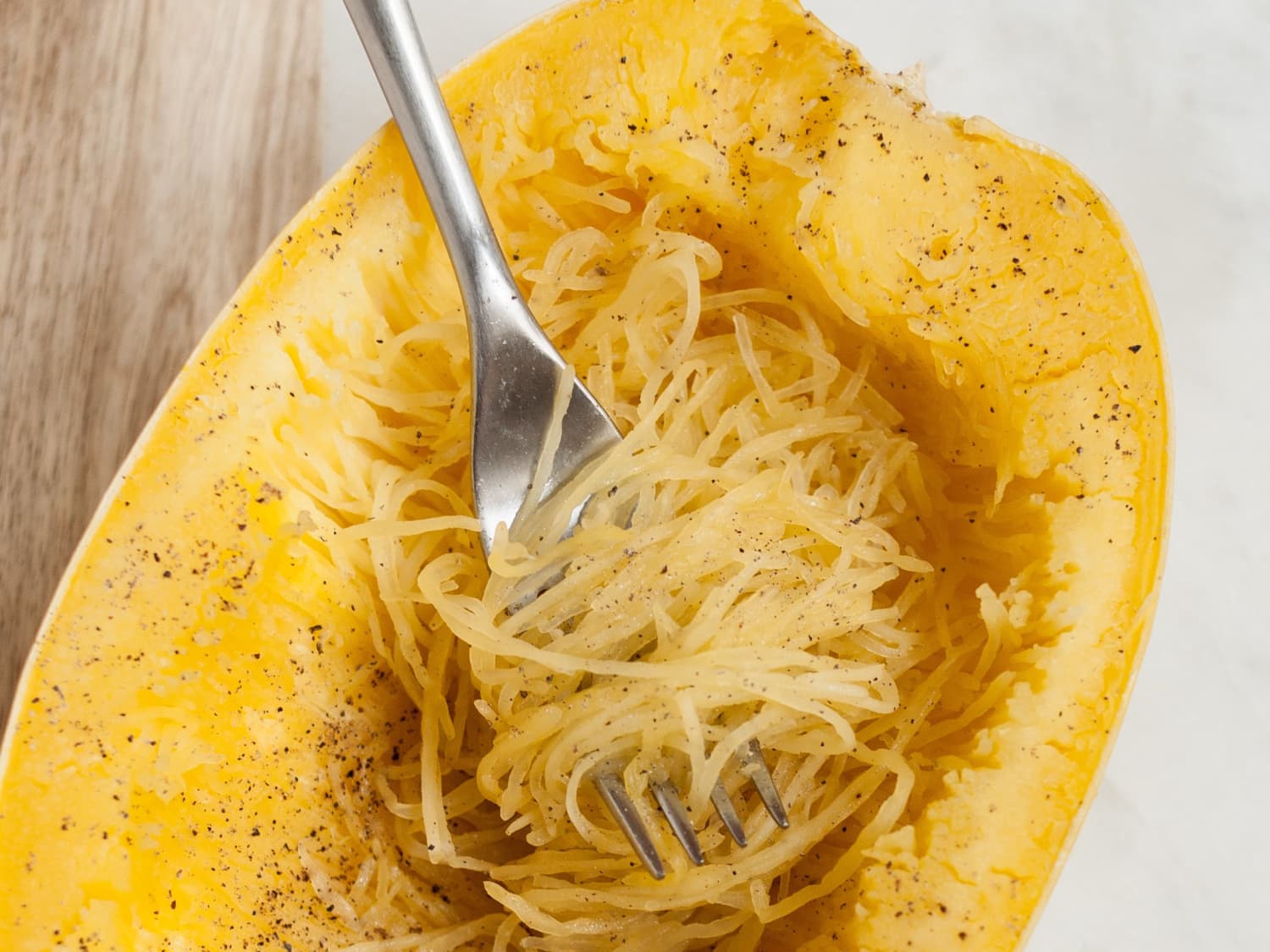 A halved spaghetti squash sitting cut-side down in a clear microwave-safe dish with a small amount of water