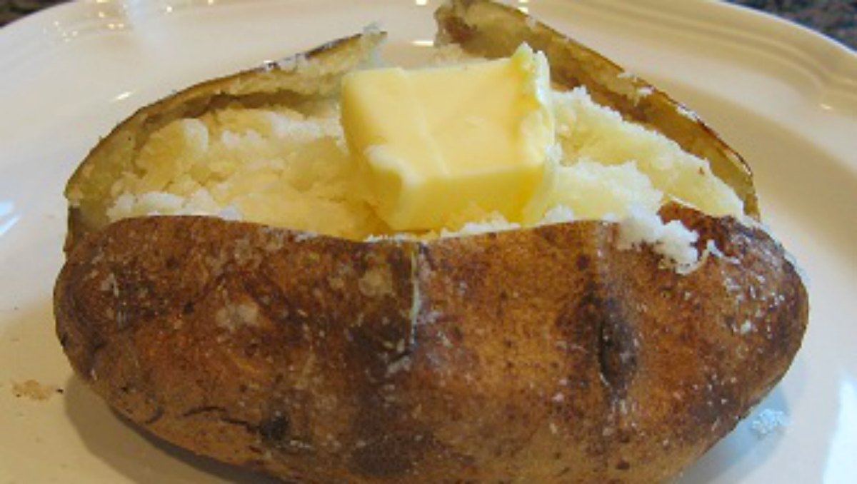 A microwave baked potato split open with butter melting into the steaming, fluffy center