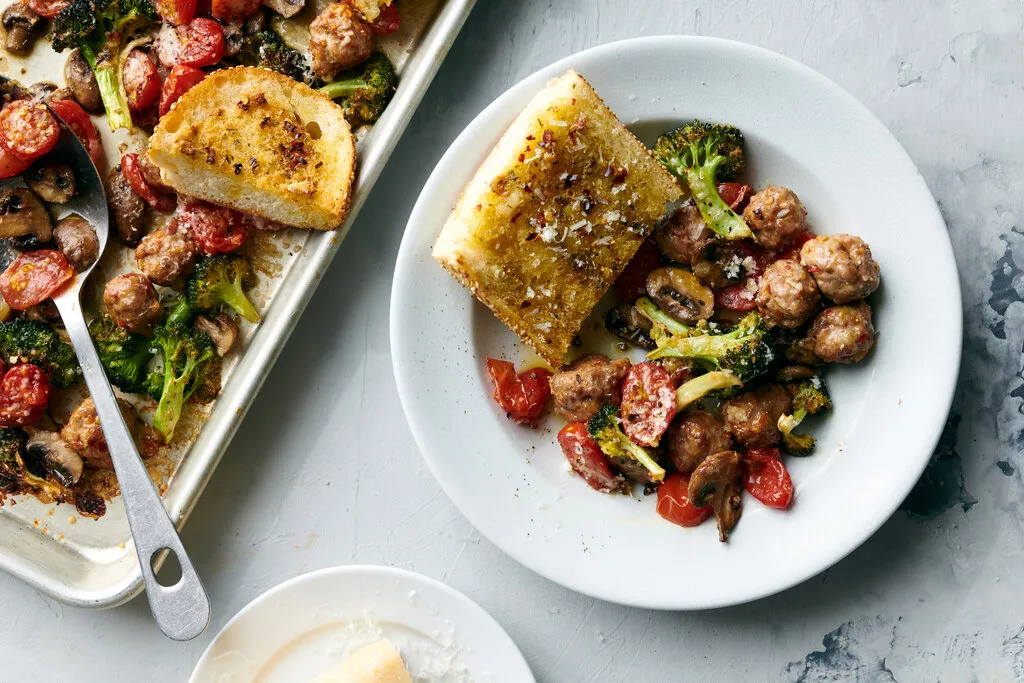 A rimmed sheet pan with evenly spaced browned meatballs just out of the oven