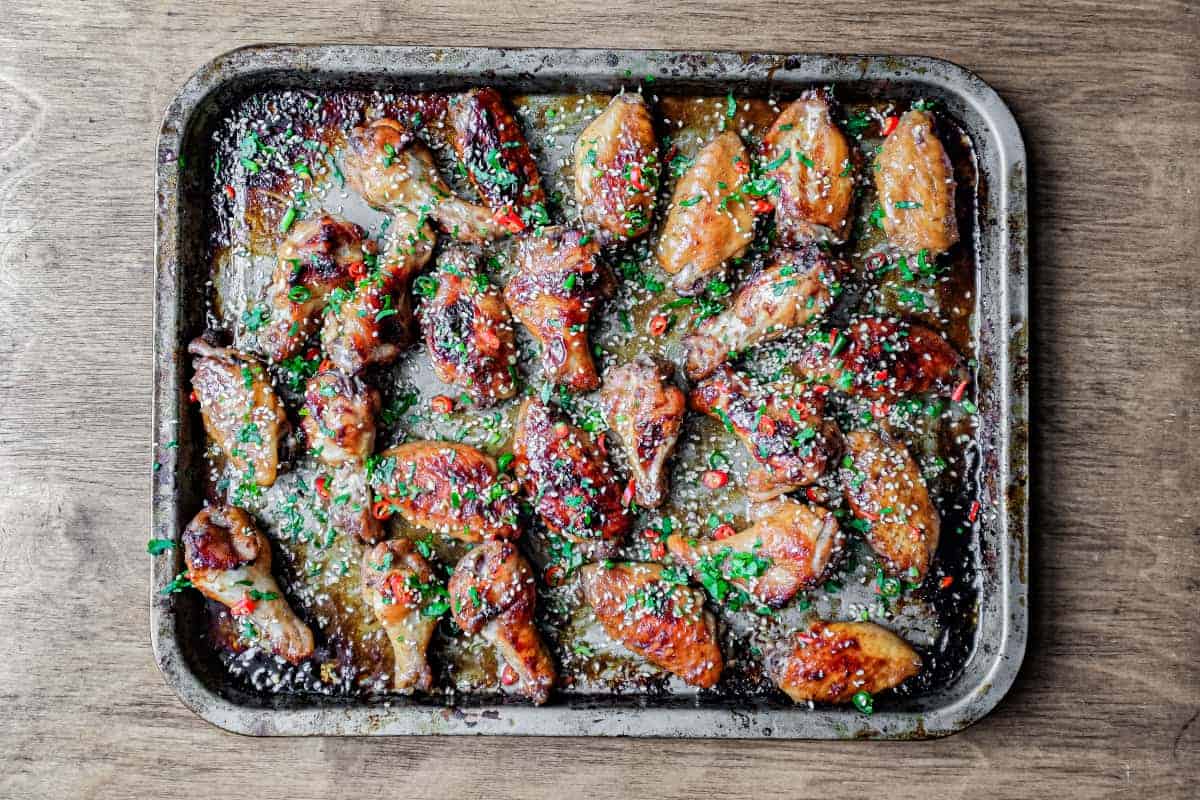 A sheet pan of golden brown baked chicken wings on a wire rack, fresh out of the oven