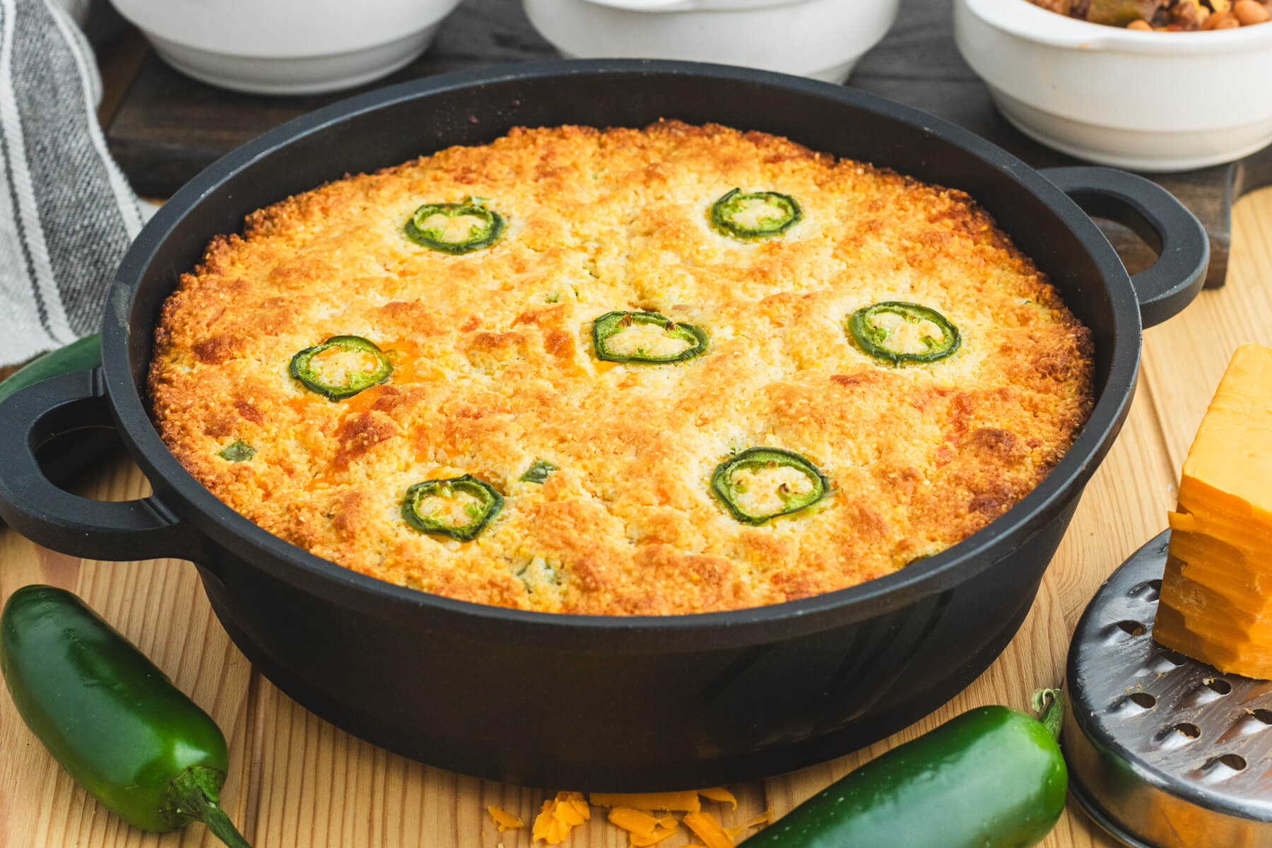 A wedge of jalapeño cheddar skillet cornbread on a plate with visible green jalapeño pieces and melted cheese pockets