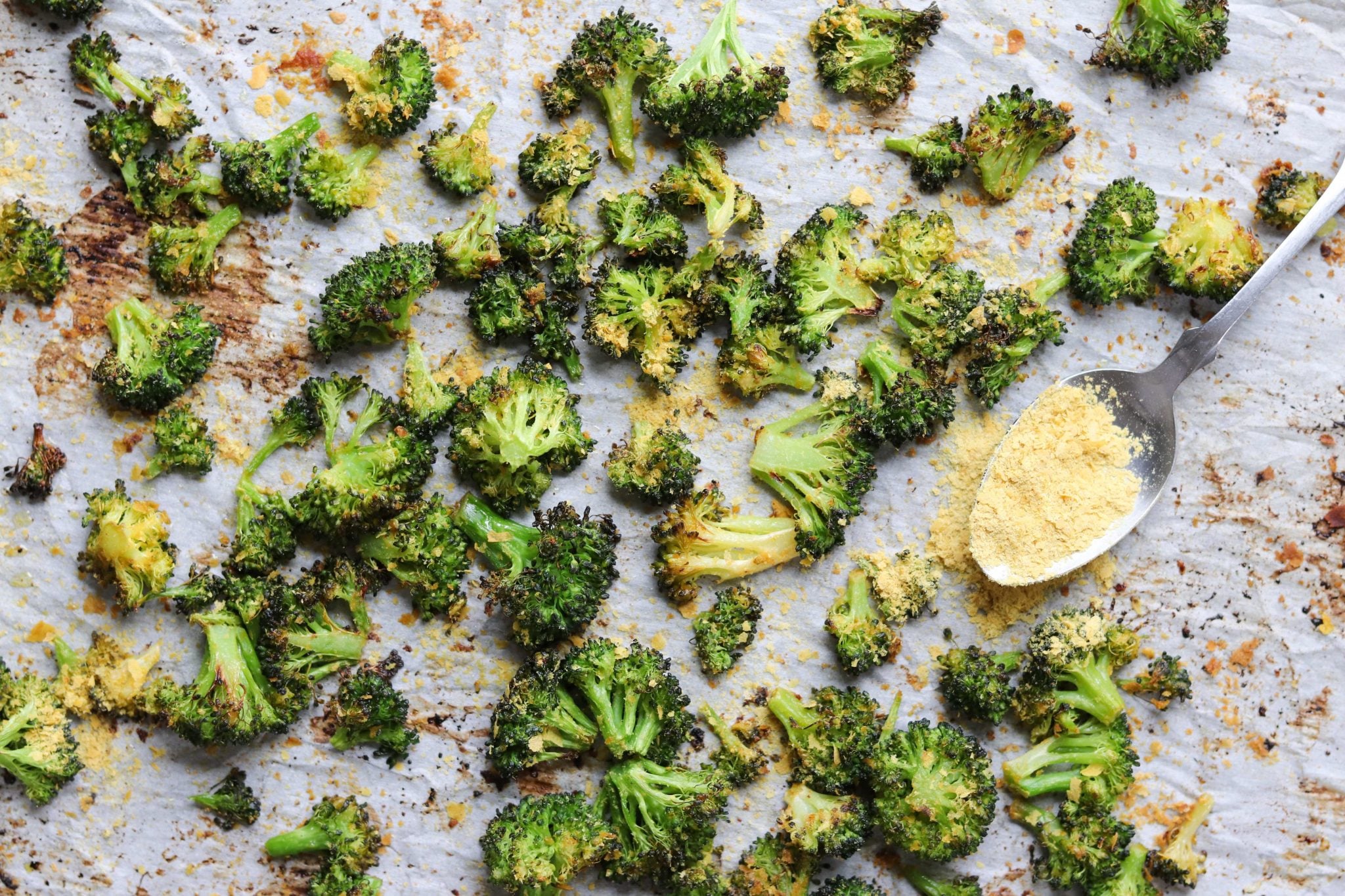Roasted broccoli spread in a single layer on a rimmed pan with space between pieces for better browning