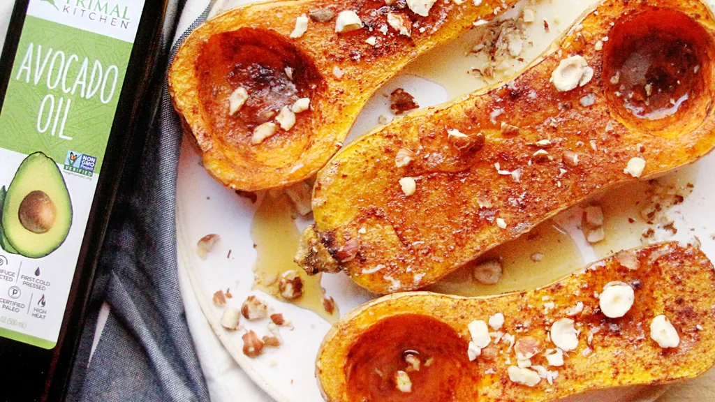 Two roasted butternut squash halves on a baking sheet with browned edges and the seed cavities emptied