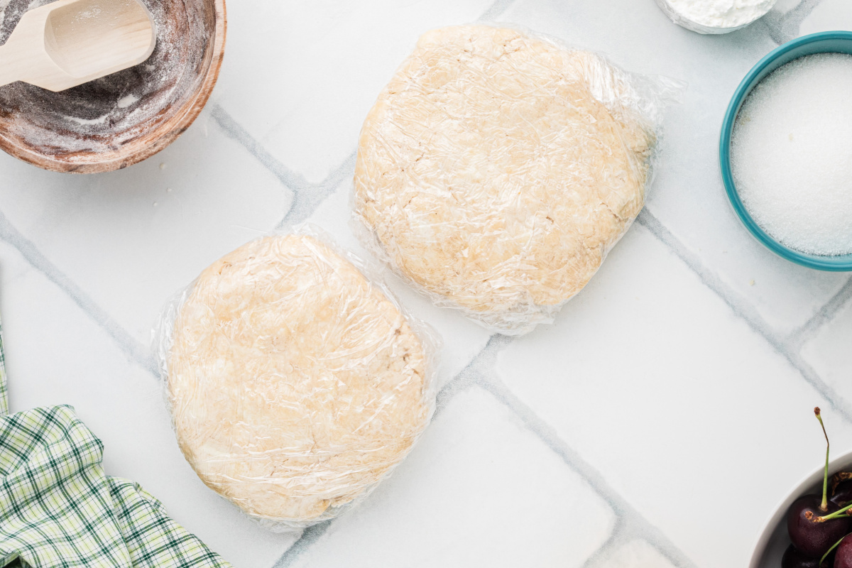 Two wrapped discs of pie dough resting on a plate inside a refrigerator
